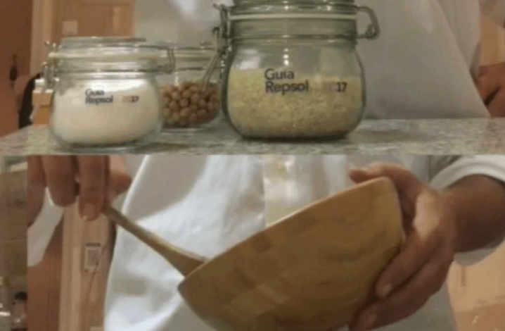 Frascos de ingredientes con la etiqueta «Guía Repsol» y manos sosteniendo un tazón de madera