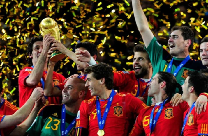 Futbolistas con camiseta roja levantando un trofeo dorado entre confeti
